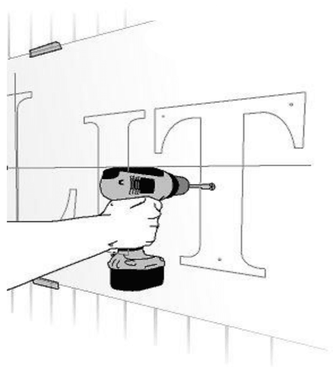 Installer drilling stand-off mounting holes for halo lit channel letters through the paper pattern